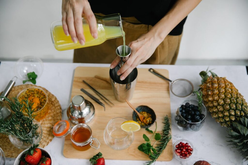 Overhead view of a refreshing juice being prepared with fresh fruits and herbs.